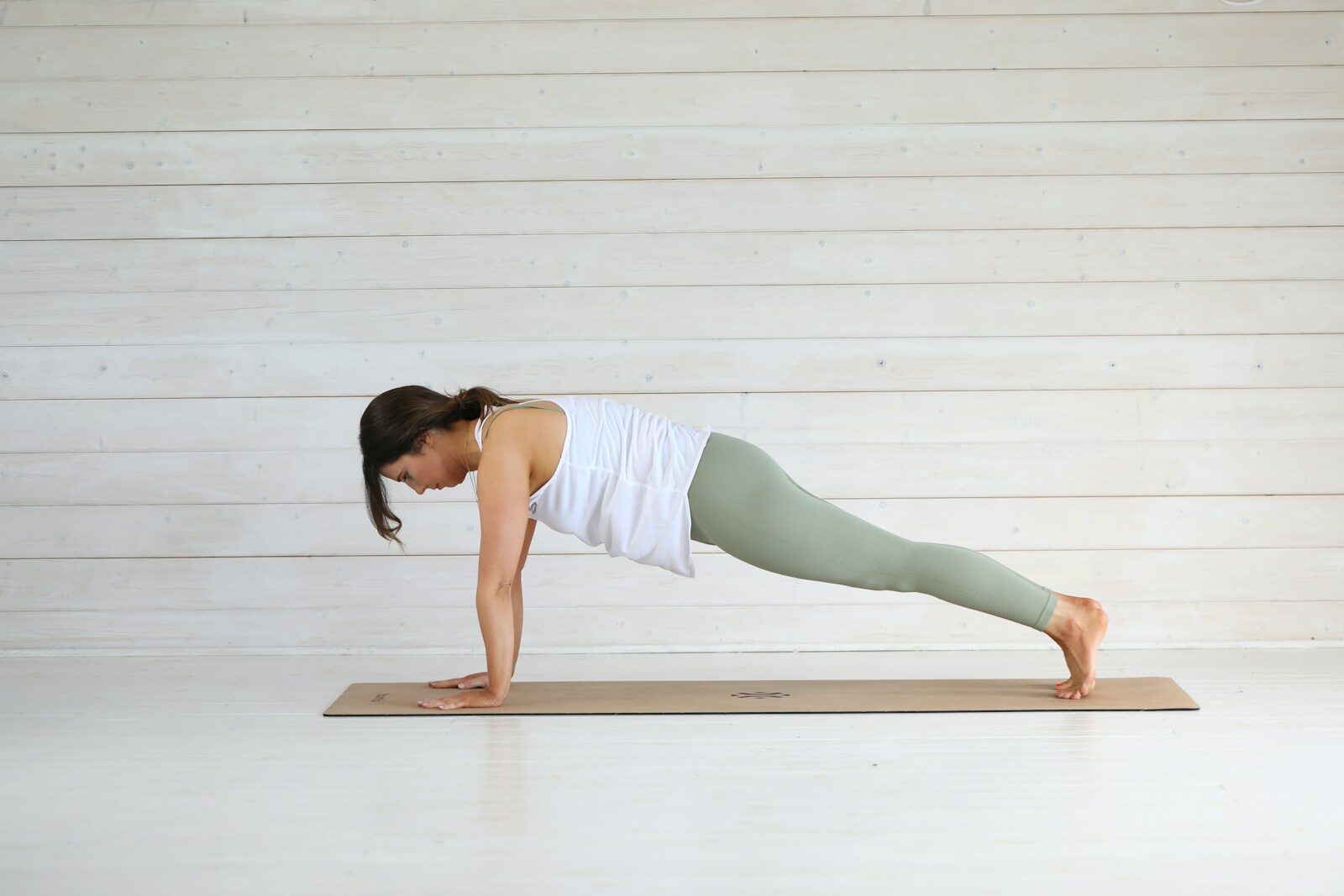 Woman performing a plank exercise on a yoga mat.